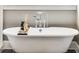 Close up of a soaking tub with chrome fixtures, a tray and decorative items next to a window at 286 Norwood Ne Ave, Atlanta, GA 30317