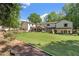 Expansive backyard with a large lawn, established trees, stone retaining wall, and covered patio at 299 Saint Marys Nw Ln, Marietta, GA 30064