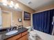 Well lit bathroom features tile floors, granite countertops, and tub with shower at 2402 Jasmine Glen Dr, Buford, GA 30519