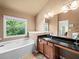 Bright bathroom featuring large window, soaking tub, tile floors and granite countertops at 2402 Jasmine Glen Dr, Buford, GA 30519