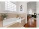Bright bathroom showcasing a soaking tub with tiled surround and a large window for natural light at 2580 Defoors Ferry Nw Rd, Atlanta, GA 30318