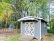 Outdoor shed with a ramp and double doors, located in a wooded backyard setting with trees and shrubbery at 4715 Howard Dr, Powder Springs, GA 30127