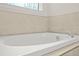 Close-up of a modern white bathtub with stylish chrome faucet and beige tile surround at 790 Riverwood Pass, Dallas, GA 30157