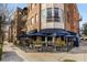 Outdoor restaurant seating with blue umbrellas and views of a brick building with wrought-iron balconies at 1195 Oglethorpe Ne Ave, Atlanta, GA 30319