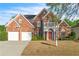 Charming two-story red brick home with a balcony, two-car garage, and mature landscaping at 1410 White Flowers Ln, Lawrenceville, GA 30045