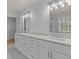 This bathroom features a double vanity with white cabinets, stone countertops, and modern fixtures at 4680 Glen Level Dr, Sugar Hill, GA 30518