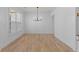 Open-concept dining room with hardwood floors, modern light fixture, and views of the lush backyard at 4680 Glen Level Dr, Sugar Hill, GA 30518