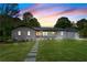 Charming single-story home featuring a brick facade, manicured lawn, and inviting walkway under a colorful sunset sky at 5036 Chestnut Forest Ln, Dunwoody, GA 30360