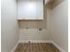 A minimalist laundry room featuring wood look ceramic tile, white walls, and cabinetry at 5036 Chestnut Forest Ln, Dunwoody, GA 30360