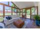 Relaxing screened porch with wood floors, white couch, leather ottoman, and open views of the wooded backyard at 5036 Chestnut Forest Ln, Dunwoody, GA 30360