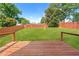 Open backyard with a wood deck and green lawn surrounded by a wooden fence under a bright sky at 628 Warren Ave, Scottdale, GA 30079