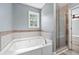 A large white tub with a tile surround and glass shower at 628 Warren Ave, Scottdale, GA 30079
