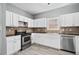 Bright kitchen features white cabinets, stone backsplash, and stainless steel appliances at 628 Warren Ave, Scottdale, GA 30079