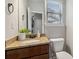 Stylish half bath with granite countertop, dark wood cabinet, and a decorative round mirror at 681 Deer Springs Way, Loganville, GA 30052