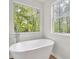 Bright bathroom featuring a modern soaking tub and a window with a lush, green view at 3905 Mill Glen Dr, Douglasville, GA 30135