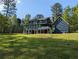 Two-story home with a back deck and porch looking out to the large grassy backyard at 5830 Wills Wood Cir, Cumming, GA 30040