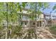 Backyard view of the home featuring a deck and access to the basement, surrounded by mature trees at 7035 W Mountain Xing, Cumming, GA 30041