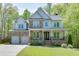 Charming two-story home with a stone and siding exterior, a welcoming front porch, and lush landscaping at 7035 W Mountain Xing, Cumming, GA 30041
