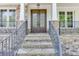 Close-up of the home's entrance, featuring a decorative front door, stone pillars, and wrought iron railings at 7035 W Mountain Xing, Cumming, GA 30041