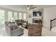 Bright living room featuring large windows, stone fireplace, ceiling fan, and comfortable seating at 7035 W Mountain Xing, Cumming, GA 30041
