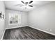 Neutral bedroom featuring dark wood-look flooring, a ceiling fan, and a large window for natural light at 1250 Parkwood Circle Se # 1110, Atlanta, GA 30339