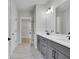 Hallway featuring a bathroom with double sinks, tile floors, and gray cabinets at 159 Sunshower Rdg, Canton, GA 30114