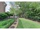 Beautifully landscaped backyard featuring lush greenery, a stone path, and wrought iron fencing at 7050 Redcliff Ct, Suwanee, GA 30024