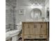 Bathroom featuring a wooden vanity, a round mirror, stylish light fixture, and tiled shower at 7050 Redcliff Ct, Suwanee, GA 30024