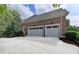 Exterior view of a three-car garage with an extended driveway and brick facade at 7050 Redcliff Ct, Suwanee, GA 30024