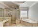 Spa-like main bathroom featuring a corner tub, frameless glass shower, and marble countertops at 7050 Redcliff Ct, Suwanee, GA 30024