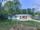 Modest one-story home featuring vinyl siding, an attached garage, and mature trees in the front yard at 1527 Keeter Rd, Canton, GA 30114