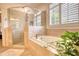 Bright bathroom featuring a glass enclosed shower and soaking tub with neutral-toned tile at 3818 Bay Forest Way, Loganville, GA 30052