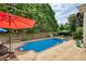 Refreshing in-ground pool surrounded by a fence and lush trees and features a concrete patio and colorful umbrellas at 3818 Bay Forest Way, Loganville, GA 30052