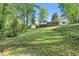 Expansive backyard with a gentle slope leading up to a charming two-story house, offering a serene outdoor space at 46 Hawkins Store Nw Rd, Kennesaw, GA 30144