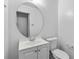 Clean, neutral-toned bathroom with modern vanity, large round mirror, and toilet, offering a functional and minimalist design at 46 Hawkins Store Nw Rd, Kennesaw, GA 30144