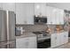 Modern kitchen featuring stainless steel appliances, gray tile backsplash, and white cabinetry at 243 Commons Ave, Woodstock, GA 30188