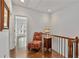 Bright hallway with hardwood floors, accent chair, and a railing leading to the lower level at 3475 Oak Valley Rd # 130, Atlanta, GA 30326