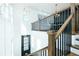 A bright foyer with a staircase and stylish wood railing leading up to the second floor and a dark front door at 6666 Sterling Dr, Sandy Springs, GA 30328