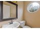 Small powder room featuring a pedestal sink, toilet, round window, and framed mirror at 861 Southland Pass, Stone Mountain, GA 30087