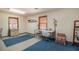 Bright bedroom featuring wood trim windows, blue carpet, a sewing table, and a comfortable floral chair at 5000 Bainbridge Sw Ct, Lilburn, GA 30047