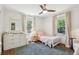 Bright bedroom featuring wood floors, two windows with curtains, a changing table, and a toddler bed at 1079 Pinedale Se Dr, Smyrna, GA 30080