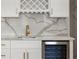 Wet bar area featuring white cabinetry, a wine fridge, gold hardware, and a designer backsplash at 1540 Brooks S Rd, Lawrenceville, GA 30045