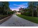 View down driveway towards two-story home at dusk with long driveway, landscaping, and wooded backdrop at 1540 Brooks S Rd, Lawrenceville, GA 30045