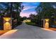 Gated entrance and long driveway leading up to a beautiful home at dusk with professional lighting at 1540 Brooks S Rd, Lawrenceville, GA 30045