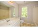 Bathroom with mirror, white vanity, toilet, tub, and a bright window at 605 Sutton Sw Way, Marietta, GA 30064