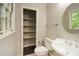 Small bathroom featuring a toilet, sink with a circular mirror, and shelving for storage at 605 Sutton Sw Way, Marietta, GA 30064