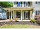Close-up of the house's covered porch with elegant columns, a black mulch garden, and access to an attached garage at 605 Sutton Sw Way, Marietta, GA 30064