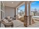 Inviting covered front porch with cozy seating area and stately brick columns overlooking the neighborhood street at 242 Cordova St, Woodstock, GA 30189
