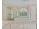 Bright bathroom with a glass-enclosed shower, soaking tub with an arched window, and neutral tile flooring at 3105 Birchton St, Johns Creek, GA 30022