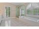 Bathroom with a soaking tub under an arched window, a separate glass-enclosed shower, and bright, neutral finishes at 3105 Birchton St, Johns Creek, GA 30022